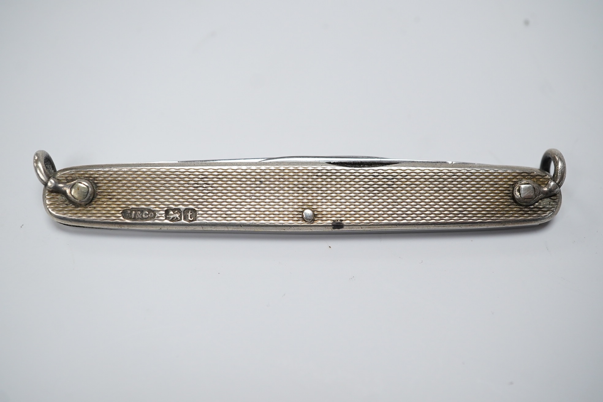 A George V engine turned silver and enamel pocket knife, decorated with R.M.S Queen Mary, the blades lifted by the handles, George Ibberson & Co, Sheffield, 1936, 76mm. Condition - poor to fair